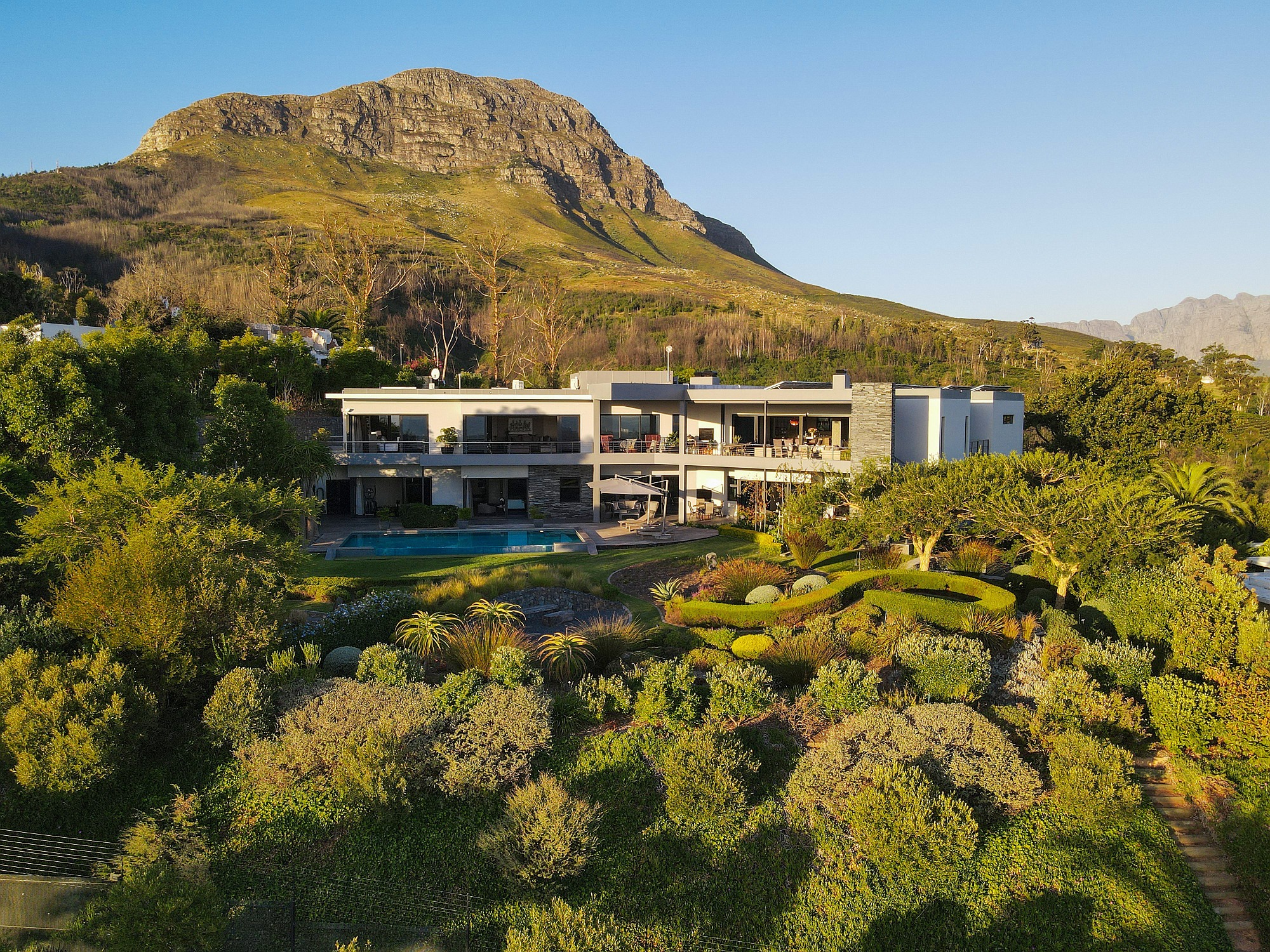 This eight-bedroom, opulent mansion in Spanish Farm, Somerset West is marketed by Pam Golding Properties at R58 million. With expansive views of the mountains and False Bay, this landmark, luxury property includes a double-volume hall, designer kitchen, cinema room, home office, indigenous garden, computerised irrigation with borehole, solar panels, sauna and solar inverter room, plus a two-bedroom, two-bathroom cottage and one-bedroom, one bathroom staff accommodation, among numerous other features. There’s also a double garage with a hydraulic lift accessible on both levels. This eight-bedroom, opulent mansion in Spanish Farm, Somerset West is marketed by Pam Golding Properties at R58 million. With expansive views of the mountains and False Bay, this landmark, luxury property includes a double-volume hall, designer kitchen, cinema room, home office, indigenous garden, computerised irrigation with borehole, solar panels, sauna and solar inverter room, plus a two-bedroom, two-bathroom cottage and one-bedroom, one bathroom staff accommodation, among numerous other features. There’s also a double garage with a hydraulic lift accessible on both levels.