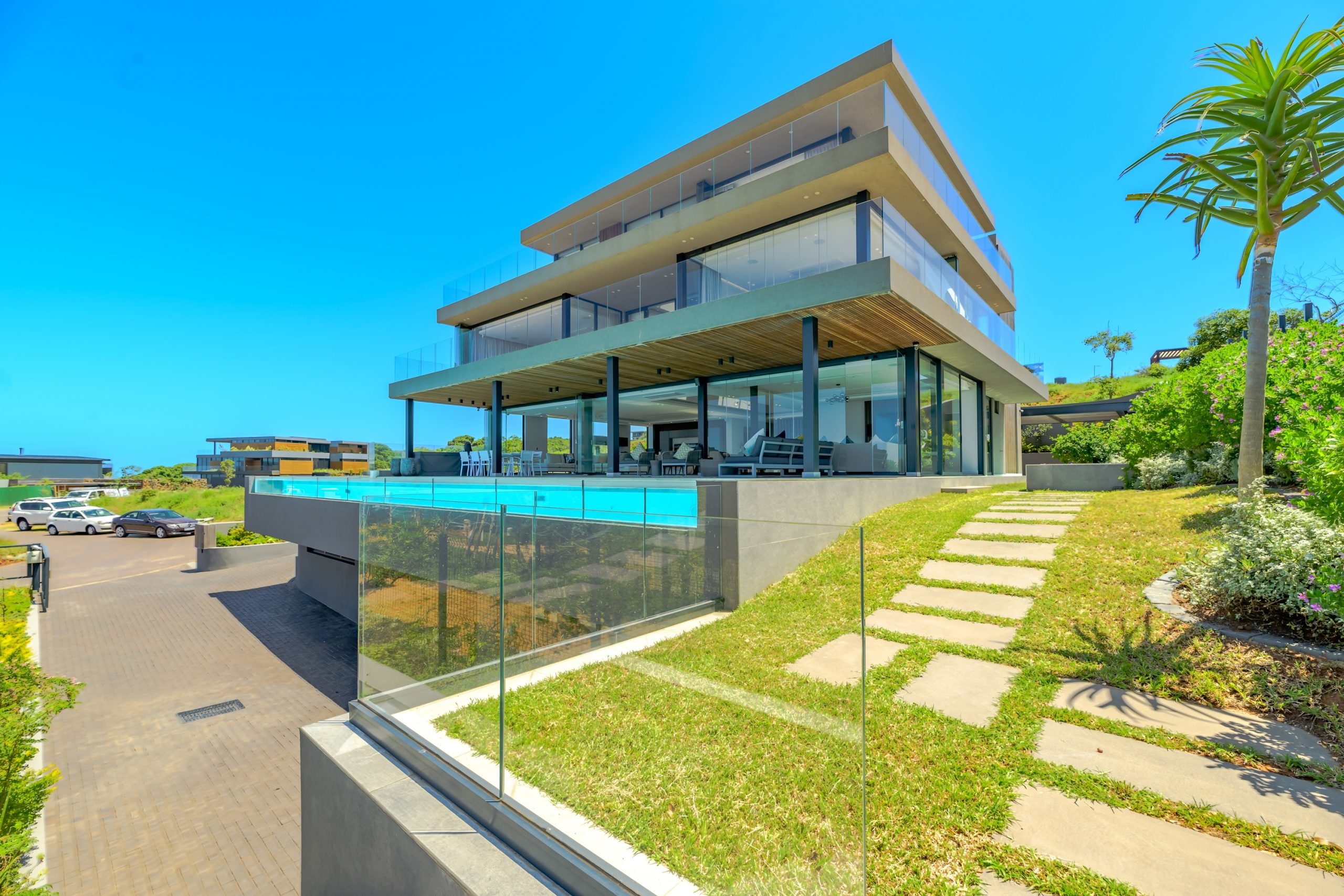 Priced at R37 million through Pam Golding Properties, this spacious and luxurious, five-bedroom, four-level home in sought-after Signature Sibaya Estate includes a grand entrance hall, central skylight, garage for 10 cars, 5-Star bar and entertainment room, fully-fitted gym, lift and staircase, large pool, gourmet kitchen, study/work-from-home space, staff accommodation, state of the art security and control room, generators, water tanks, wraparound water feature/float and spectacular views of the ocean and a green belt. The selling price includes luxurious, custom-made furniture. Priced at R37 million through Pam Golding Properties, this spacious and luxurious, five-bedroom, four-level home in sought-after Signature Sibaya Estate includes a grand entrance hall, central skylight, garage for 10 cars, 5-Star bar and entertainment room, fully-fitted gym, lift and staircase, large pool, gourmet kitchen, study/work-from-home space, staff accommodation, state of the art security and control room, generators, water tanks, wraparound water feature/float and spectacular views of the ocean and a green belt. The selling price includes luxurious, custom-made furniture.